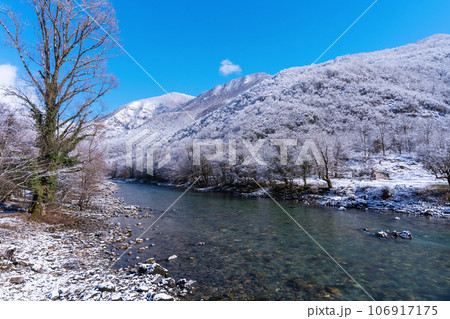 Beautiful winter landscape with emerald mountain river and snow-covered shores on a sunny day. Great natural background with copy space for your design. 106917175