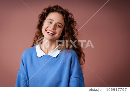 Happy smiling young adult woman wearing winter blue sweater indoors looking at camera with joyful smile 106917797