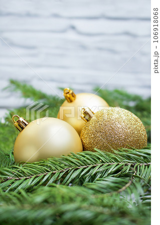 Golden balls in nest of fir branches against white wall. New Year, Christmas, holiday, business. Copy space 106918068