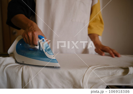 wuman ironing white clothes on the ironing board. Ironing process. Housewife ironing clothes wuman ironing white clothes on the ironing board. Ironing process. Housewife ironing clothes 106918386