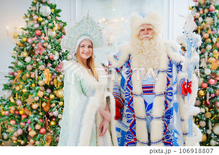 a Father Frost and Snow Maiden in blue costume in the room with christmas trees  106918807