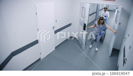 Clinic corridor: Male nurse pushes wheelchair 106919047