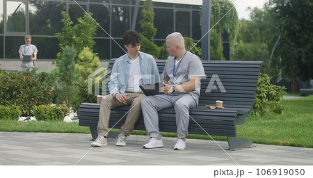 Doctor with tablet sits with patient on bench Doctor with tablet sits with patient on bench 106919050