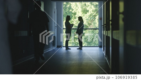 Medical staff and patients walk in dark clinic corridor 106919385