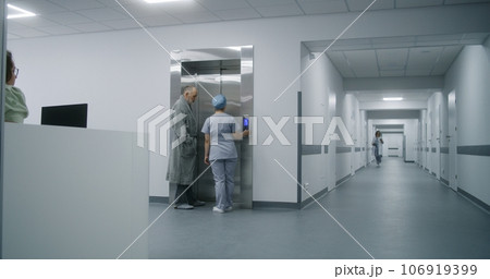 Nurse with old patient wait for elevator in medical center hallway 106919399