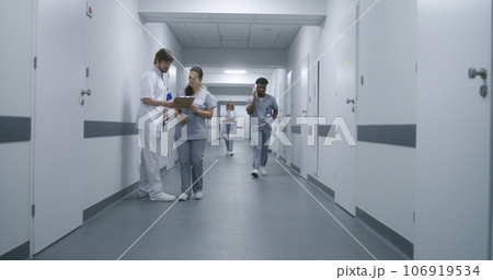 Multiracial medical staff walk clinic corridor 106919534