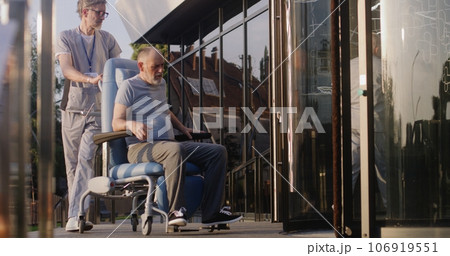 Two doctors take elderly man with disability to the clinic Two doctors take elderly man with disability to the clinic 106919551