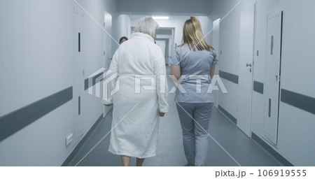 Nurse helps elderly woman to get to hospital ward 106919555