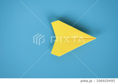 Top view of yellow paper airplane on blue background. Space for text or ideas. Top view of yellow paper airplane on blue background. Space for text or ideas. 106920495