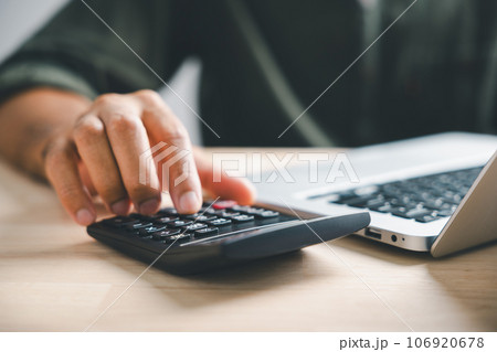 Hand on calculators, aiming for home refinance. Wooden house model, buy or rent note on desk. Concept of saving to buy property, wise mortgage payment. Tax, credit analysis for financial benefit. Hand on calculators, aiming for home refinance. Wooden house model, buy or rent note on desk. Concept of saving to buy property, wise mortgage payment. Tax, credit analysis for financial benefit. 106920678