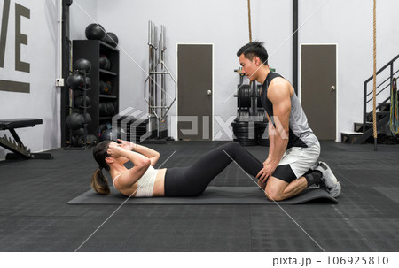Fit couple exercising together in a well-equipped gym, engaged in a dynamic strength training workout. An image reflecting teamwork, motivation, and a healthy lifestyle. Fit couple exercising together in a well-equipped gym, engaged in a dynamic strength training workout. An image reflecting teamwork, motivation, and a healthy lifestyle. 106925810