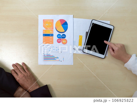 Closeup businesswoman in suit  pointing at tablet computer. Document, graph and chart are on wooden table. Top View 106925822