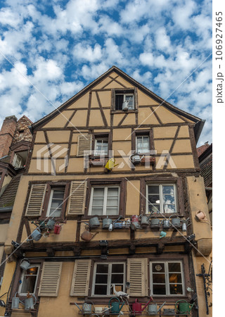 Facade of a traditional Alsatian house decorated with old watering cans in the city center. 106927465