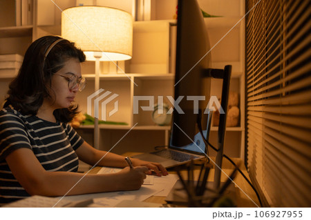 Late-Night Online Education, Dedicated Young Woman Studying Online Late at Night in Her Home Office, Work for home. Late-Night Online Education, Dedicated Young Woman Studying Online Late at Night in Her Home Office, Work for home. 106927955