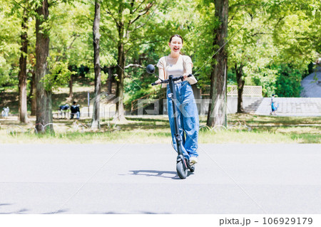 電動キックボードで爽やかに走る若い女性 106929179