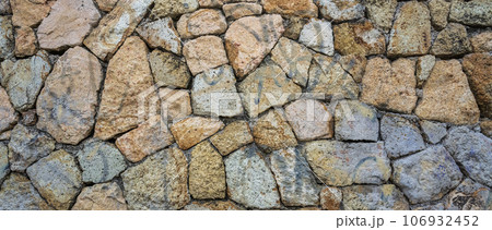 Fragment of a natural stone wall as a background or texture. The structure of the stone wall. Old castle stone wall texture background. 106932452