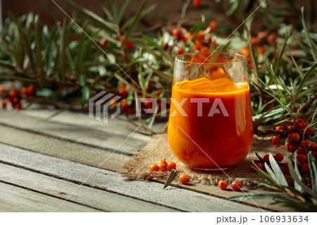 Glass of sea buckthorn juice with fresh berries. 106933634