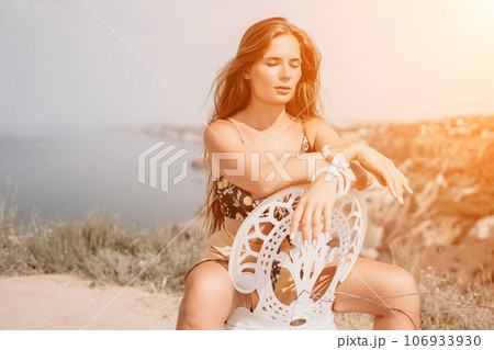 Happy boho woman portrait. Boho chic fashion style. Outdoor photo of free happy woman with long hair, sunny weather outdoors with sea mountains nature beautiful background. 106933930