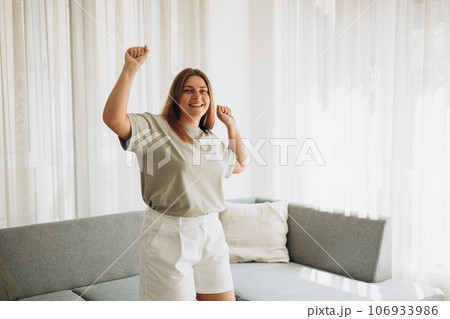 Portrait of happy woman dancing, rejoicing and triumphing, feeling upbeat at home. Copy space. Young female enjoying carefree and leisure weekend Portrait of happy woman dancing, rejoicing and triumphing, feeling upbeat at home. Copy space. Young female enjoying carefree and leisure weekend 106933986