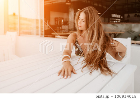 Happy woman portrait in cafe. Boho chic fashion style. Outdoor photo of young happy woman with long hair, sunny weather outdoors sitting in modern cafe. 106934018
