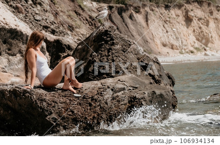 Woman travel sea. Happy tourist in white bikini enjoy taking picture outdoors for memories. Woman traveler posing on the beach at sea surrounded by volcanic mountains, sharing travel adventure journey Woman travel sea. Happy tourist in white bikini enjoy taking picture outdoors for memories. Woman traveler posing on the beach at sea surrounded by volcanic mountains, sharing travel adventure journey 106934134