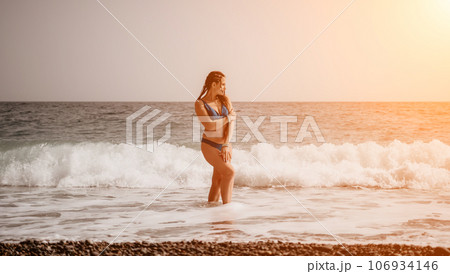 A tourist woman in blue bikini on beach enjoys the turquoise sea during her summer holiday. Rear view. Beach vacation. woman with braids dreadlocks standing with her arms raised enjoying beach ocean. A tourist woman in blue bikini on beach enjoys the turquoise sea during her summer holiday. Rear view. Beach vacation. woman with braids dreadlocks standing with her arms raised enjoying beach ocean. 106934146