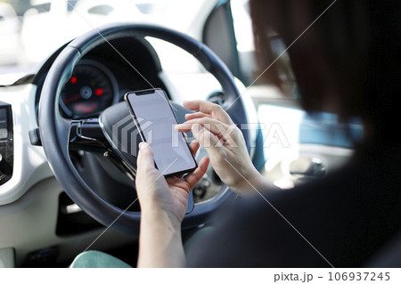 運転席でスマホを使う女性 106937245