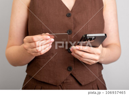 Hand holding phone and bank card, paying online 106937465