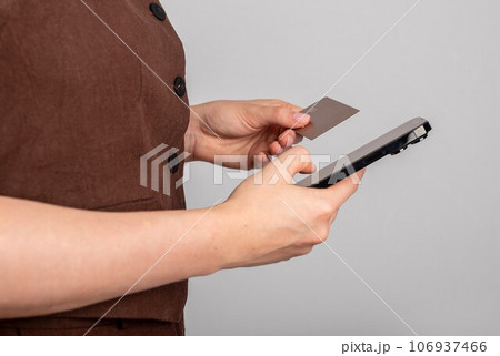 Hand holding mobile phone and bank card, paying online through internet 106937466