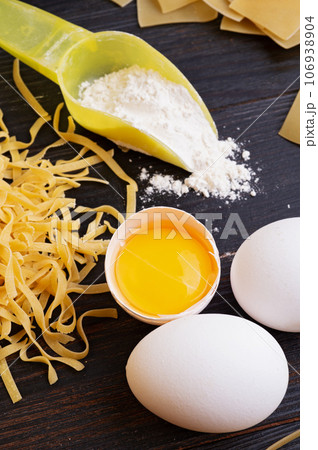 variety of types and shapes of italian pasta on dark wooden table with ingredients, flour and eggs. dry pasta background. close up 106938904