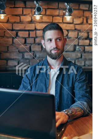 Handsome young man working on laptop while enjoying coffee in cafe 106940257