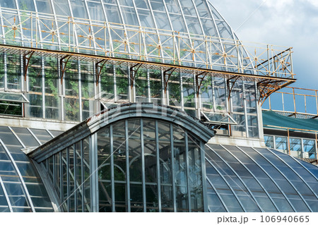view of the glass walls and domes of a large vintage palm greenhouse 106940665