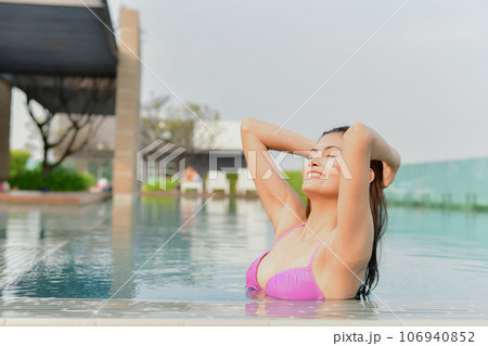 Asian woman in swimsuit emerging from pool. She is playing in the water having fun. 106940852