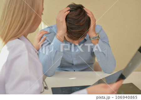 Doctor comforting patient in hospital. The patient is worried about his illness. 106940865