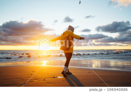 Tourist in yellow jacket enjoying sea landscape at sunset. Lifestyle, travel, nature, active life. Tourist in yellow jacket enjoying sea landscape at sunset. Lifestyle, travel, nature, active life. 106940886