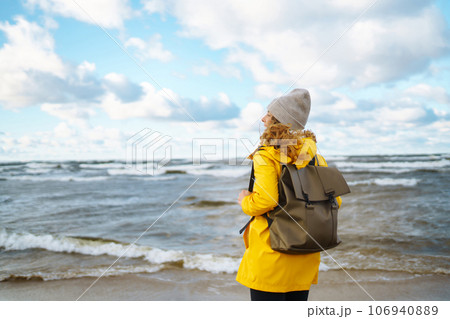 Happy tourist in a yellow jacket enjoying sea landscape at sunset. Travelling, lifestyle, adventure. Happy tourist in a yellow jacket enjoying sea landscape at sunset. Travelling, lifestyle, adventure. 106940889