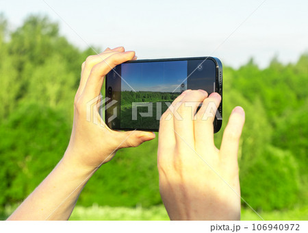 Hands holding mobile phone, taking photo of nature Hands holding mobile phone, taking photo of nature 106940972
