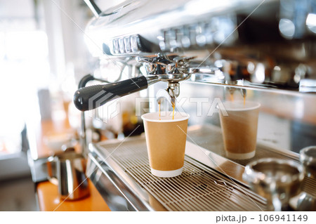 Hot delicious coffee pouring from coffee machine into coffee cup. Hot delicious coffee pouring from coffee machine into coffee cup. 106941149