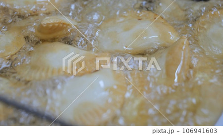 The process of cooking in the kitchen. Pasties with meat fried in sunflower oil, deep-fried. Fast food, junk food. Tatar, Caucasian, Greek cuisine. The process of cooking in the kitchen. Pasties with meat fried in sunflower oil, deep-fried. Fast food, junk food. Tatar, Caucasian, Greek cuisine. 106941603