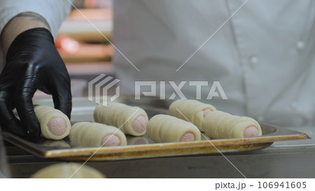 The cook prepares sausages in the dough, the baker makes sausages in the dough, the chef prepares hot dogs 106941605