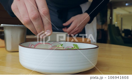 Healthy organic food. The cook prepares a salad with cucumber and radish, the cook prepares a light salad, vegetarian food, the cook presents a delicious dish. 106941608