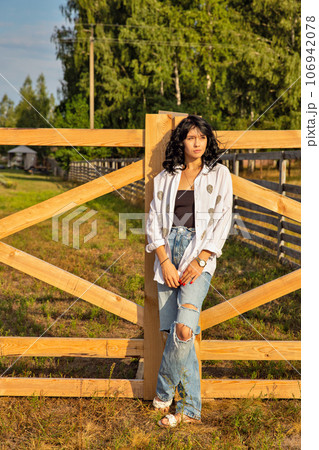 Beautiful young caucasian woman standing at the ranch gate. Beautiful young caucasian woman standing at the ranch gate. 106942078