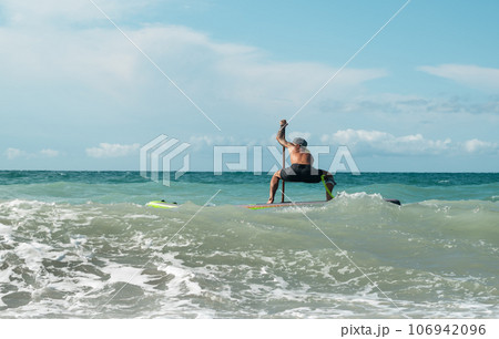 athletic wiry surfer guy swims with a paddle on a sapboard in the sea 106942096