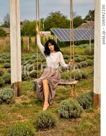 Beautiful young caucasian woman sitting on a wooden swing. 106942100