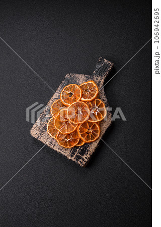 Dried round slices of tangerine, orange or lemon on a dark concrete background 106942695