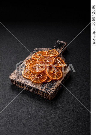 Dried round slices of tangerine, orange or lemon on a dark concrete background 106942696