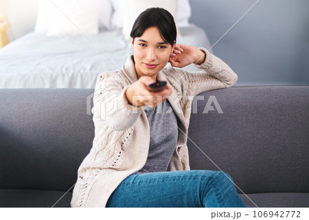 Watching tv, portrait of happy woman with remote and in bedroom of their home. Entertainment or comfortable relaxation, news or television and cheerful female person streaming movie or series Watching tv, portrait of happy woman with remote and in bedroom of their home. Entertainment or comfortable relaxation, news or television and cheerful female person streaming movie or series 106942772