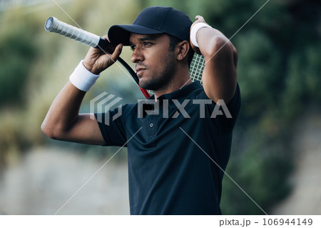 Young tennis player adjusting his cap during a match Young tennis player adjusting his cap during a match 106944149