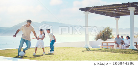 Family, father and playing football at beach on vacation, having fun and bonding. Soccer, sports and happy dad play with kids or children for exercise, care and enjoying holiday at seashore in summer 106944296