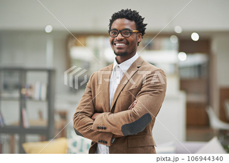 Looking sharp and feeling great. Cropped portrait of a confident young businessman standing with his arms folded in his office. 106944340